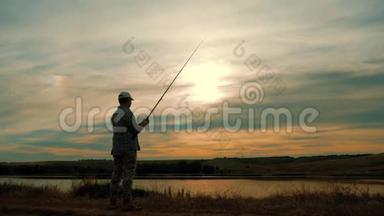 在美丽的日落中享受钓鱼的人剪影。